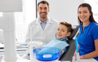 a boy with a male dentist and female dental assistant during a dental visit.