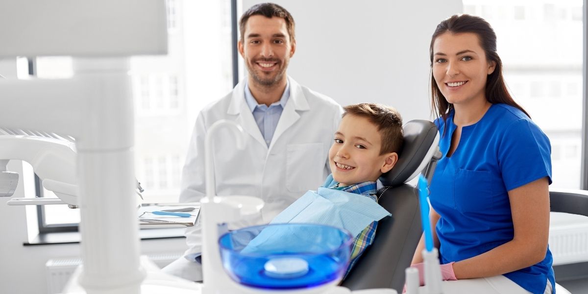 a boy with a male dentist and female dental assistant during a dental visit.